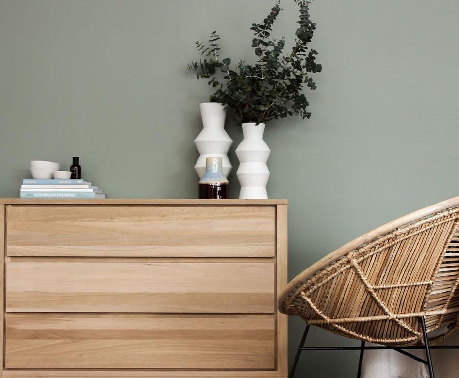 Chair and dresser against a sage wall 