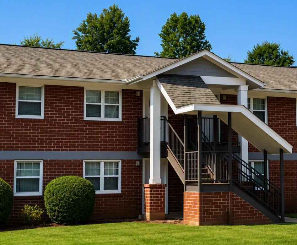 a brick house with a lawn and trees in the background